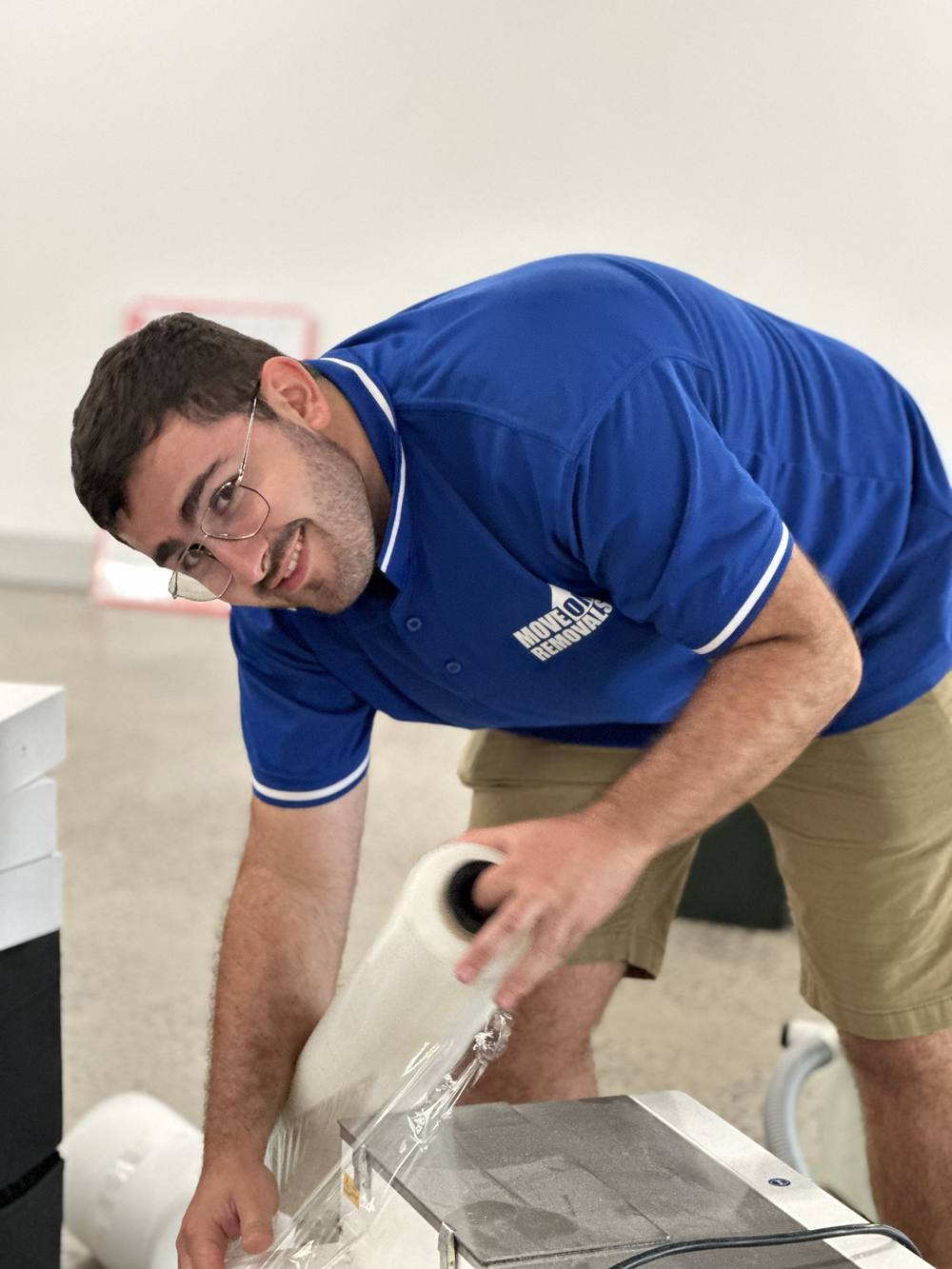 Mover wrapping furniture in protective stretch film