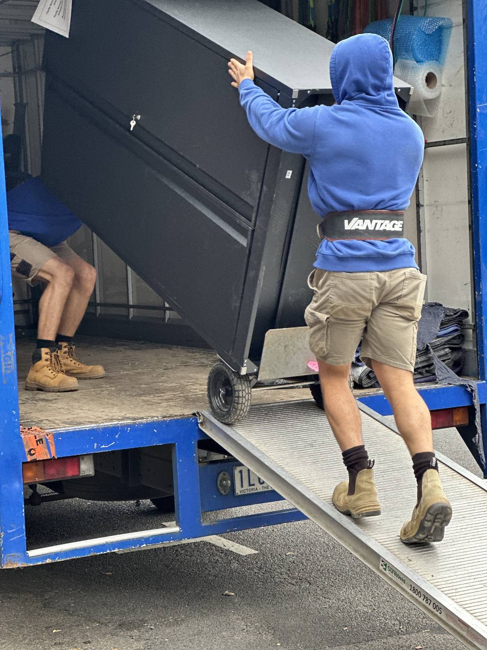 Mover securing a filing cabinet on the truck ramp