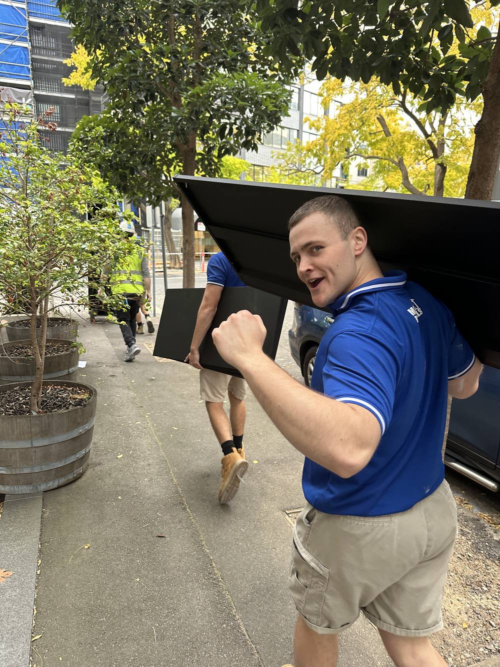 Mover carrying a filing cabinet along the footpath