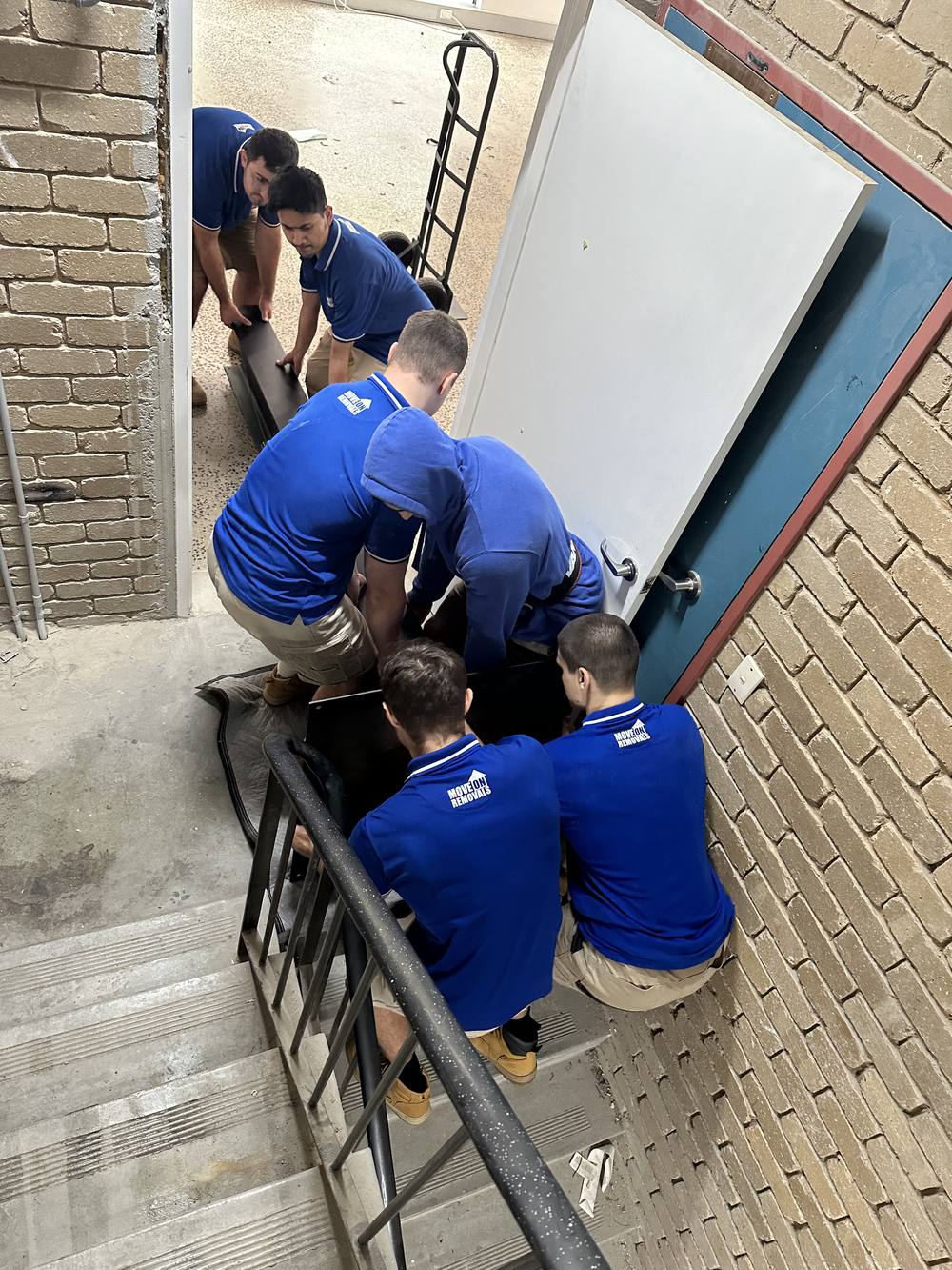 Move On Removals crew carrying office furniture down a stairwell