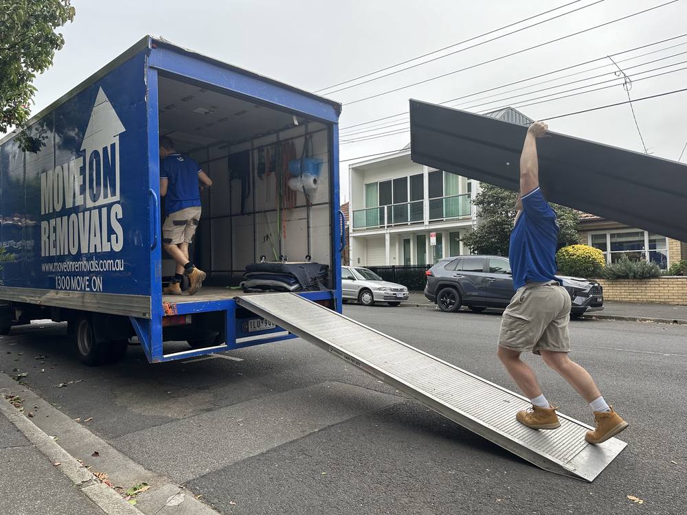Move On Removals branded truck with ramp down, crew loading furniture