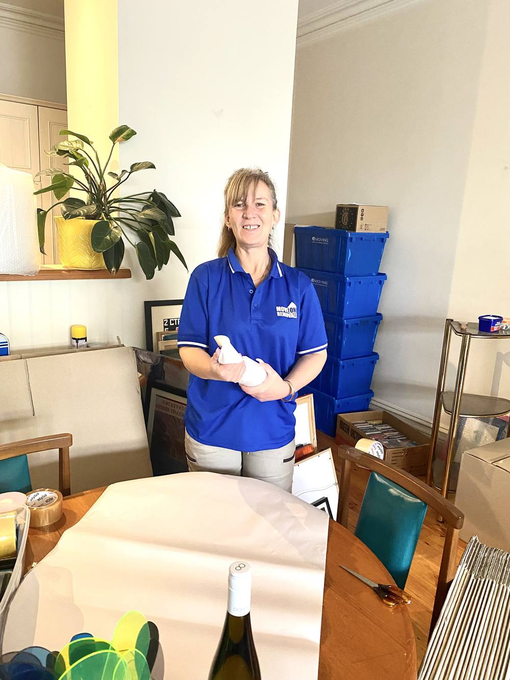 Move On Removals team member wrapping an item near stacked crates