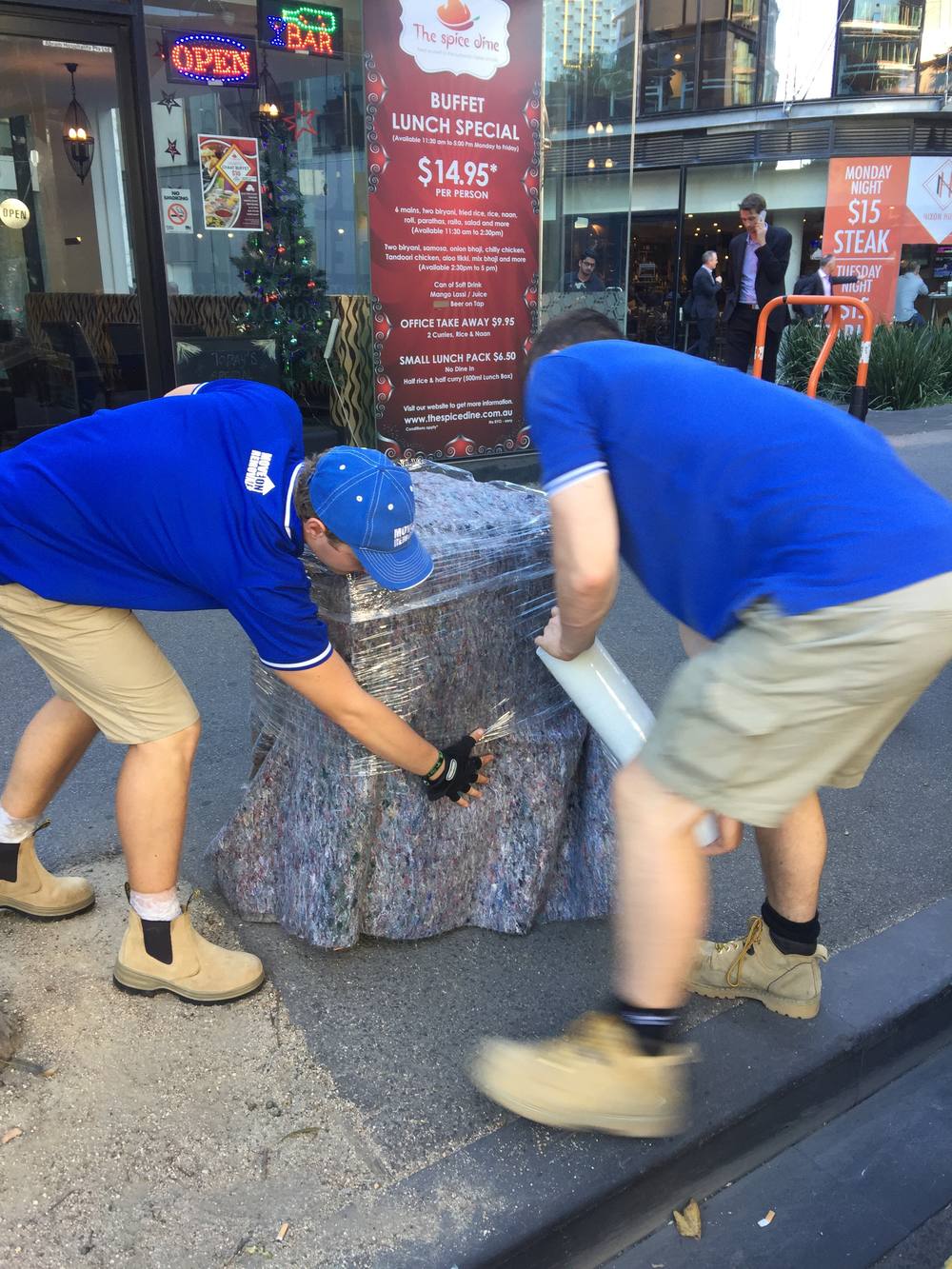 Move On Removals crew wrapping furniture in protective film on the street