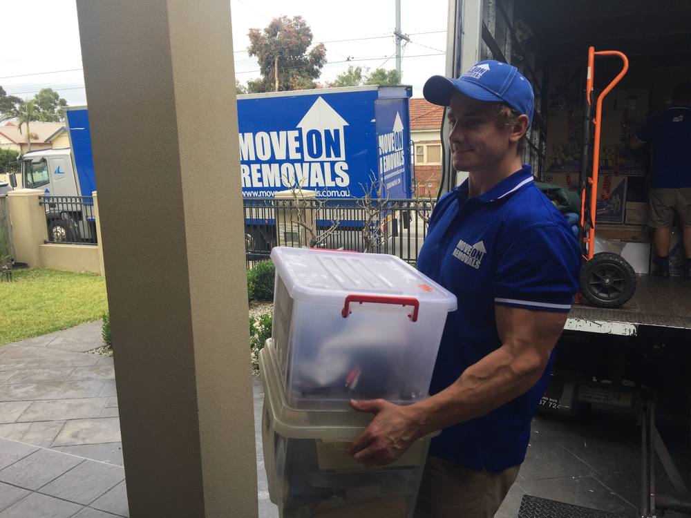 Move On Removals crew member carrying storage bins with the branded truck in the background